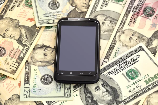 Teléfono móvil con pantalla táctil y dólares — Foto de Stock