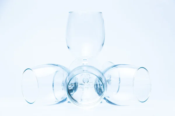 Copos de vinho de pé e mentira simetricamente no branco — Fotografia de Stock