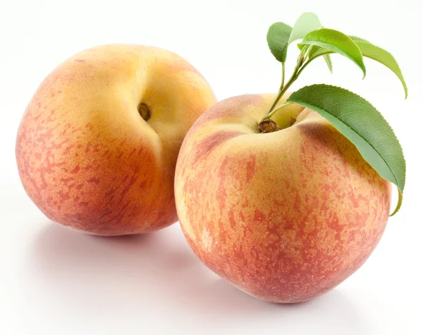 Zwei reife Pfirsiche mit Blättern — Stockfoto