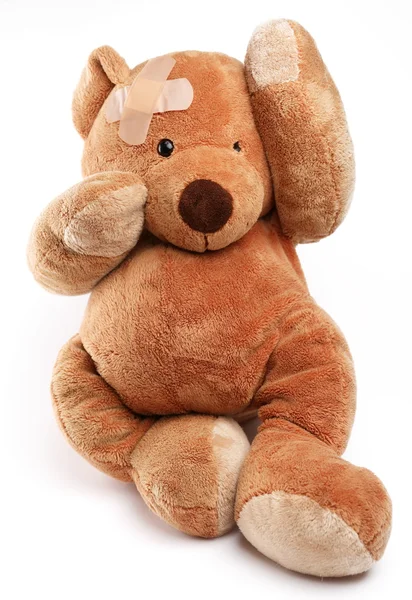 Kranker Teddybär mit Gips auf dem Kopf. isoliert auf weißem Hintergrund. — Stockfoto