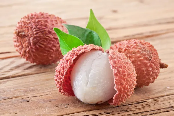 Lychee with leaves on a wooden table. — Stock Photo, Image