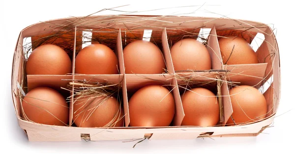 Яйца с соломинкой в деревянной корзине на белом фоне . — стоковое фото