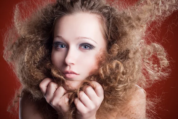 Krásná mladá dívka s kudrnatými vlasy na oranžovém pozadí — Stock fotografie