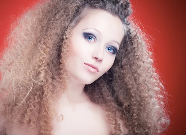 Красива молода дівчина з кучерявим волоссям на помаранчевому фоні — стокове фото