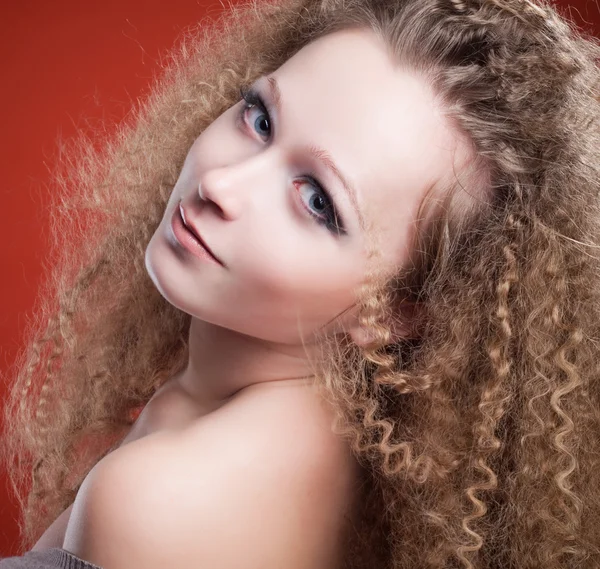 Vacker ung tjej med lockigt hår på en orange bakgrund — Stockfoto