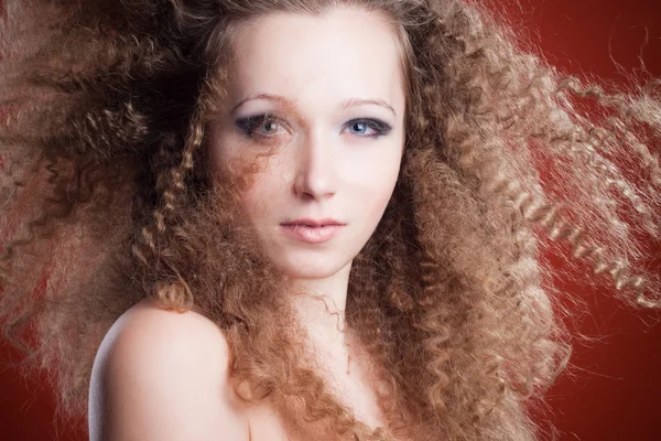 Hermosa joven con el pelo rizado sobre un fondo naranja —  Fotos de Stock