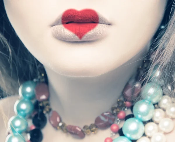 Retrato creativo de una hermosa joven con un corazón pintado en los labios —  Fotos de Stock