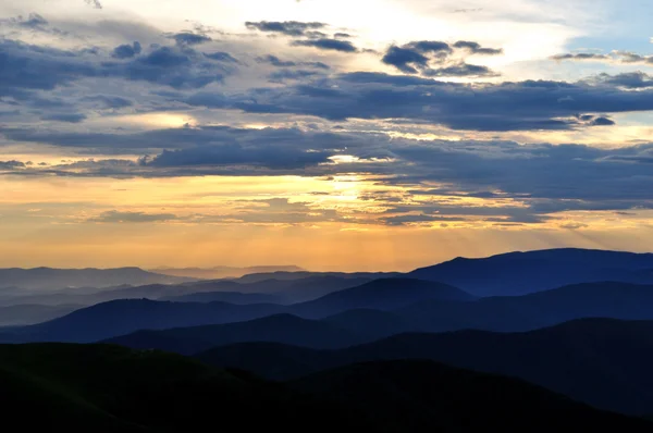 Zachmurzony zachód słońca nad szmaragd górskie grzbiety — Zdjęcie stockowe