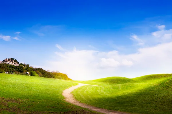 Spring landscape with green grass, road and clouds — Stock Photo, Image
