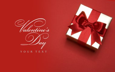 Art Valentines day golden gift box with a red bow on red background clipart