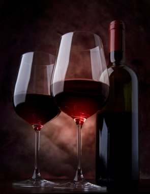 Art wine glasses with red wine and bottle of wine on the table clipart