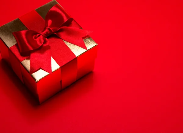 Sanat altın hediye kutu kırmızı zemin üzerine kırmızı yay ile — Stok fotoğraf