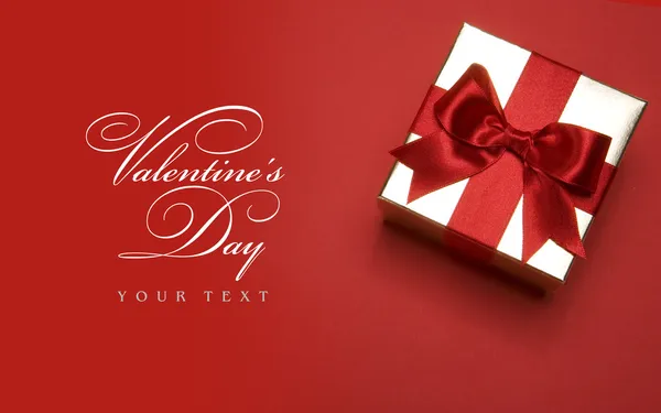 Kunst Valentinstag goldene Geschenkschachtel mit roter Schleife auf rotem Hintergrund — Stockfoto