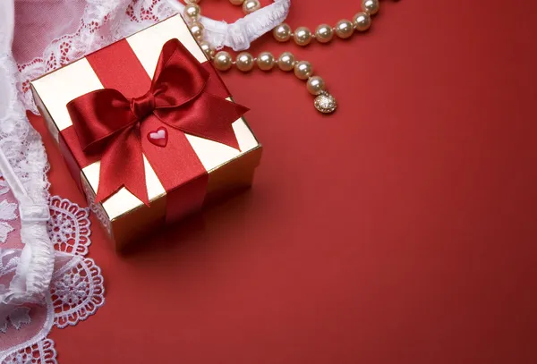 День святого Валентина золотая коробка подарка с луком на красном фоне — стоковое фото