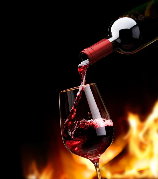 Kunst gießt Rotwein aus der Flasche in Weinglas — Stockfoto