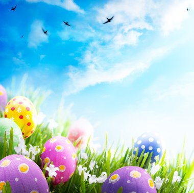 Art Easter eggs decorated with flowers in the grass on blue sky