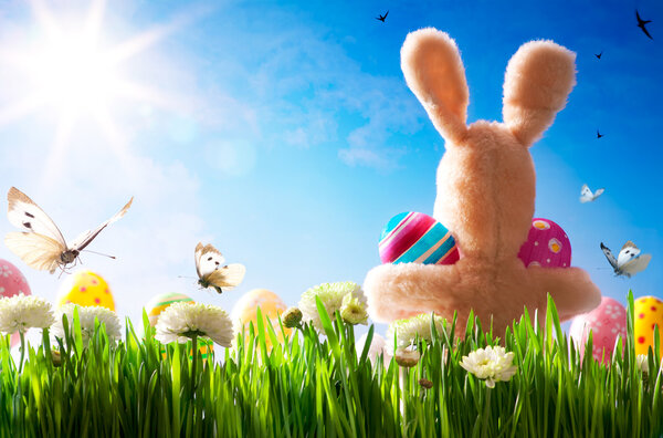 Пасхальный кролик и пасхальные яйца на зеленой траве
