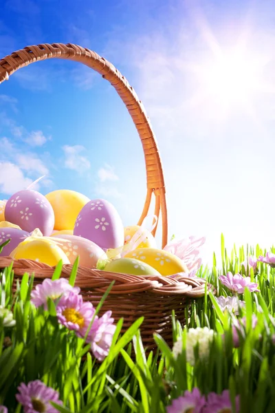Пасхальная корзина с пасхальными яйцами на весеннем газоне — стоковое фото