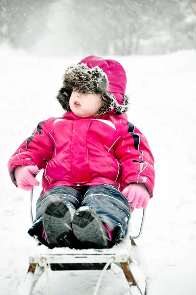 Kleines Mädchen auf Schlitten im Schneeanzug — Stockfoto