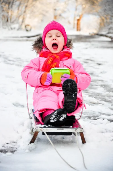Маленькая девочка на санях в снежном костюме — стоковое фото
