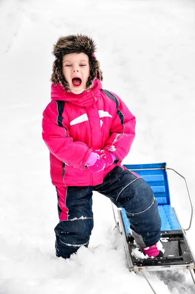 Kleines Mädchen neben Schlitten im Schneeanzug schreit — Stockfoto