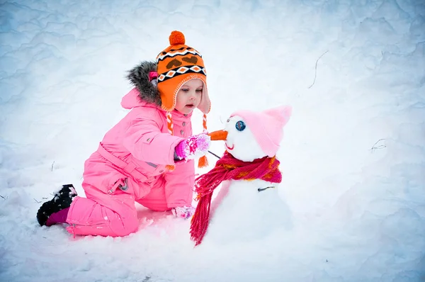 Weinig meisje maken sneeuwpop — Stockfoto