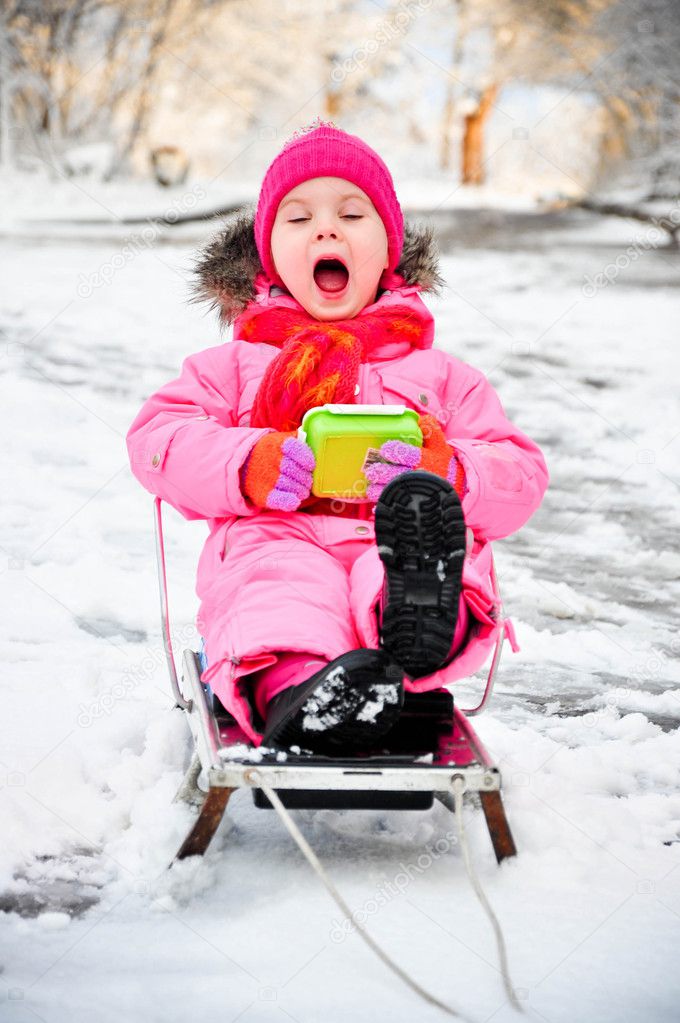 Little girl on sleigh in snowsuit