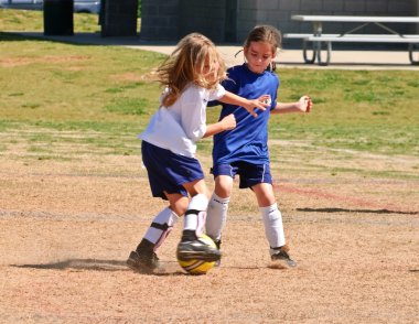 Two Young Girls Fighting for the Soccer Ball clipart