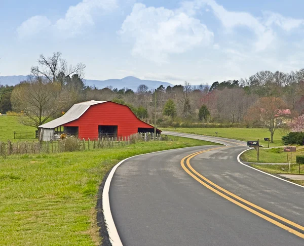 Red Barn em uma estrada curva — Fotografia de Stock