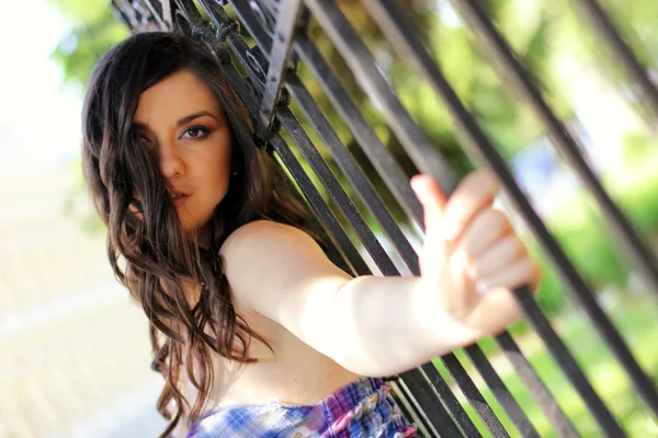 Jong meisje door het hek — Stockfoto
