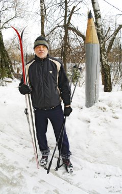 parkta bir kayak ile kışın duran yaşlı bir adam