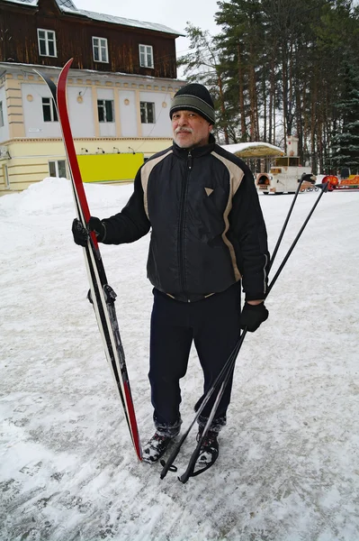 An elderly man standing with a cross-country skiing in the park in winter — Stock Photo, Image