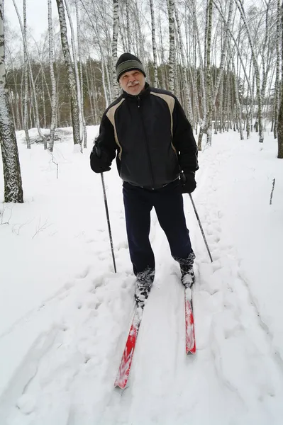 Een oudere man staat op het langlaufen in het park in de winter — Stockfoto