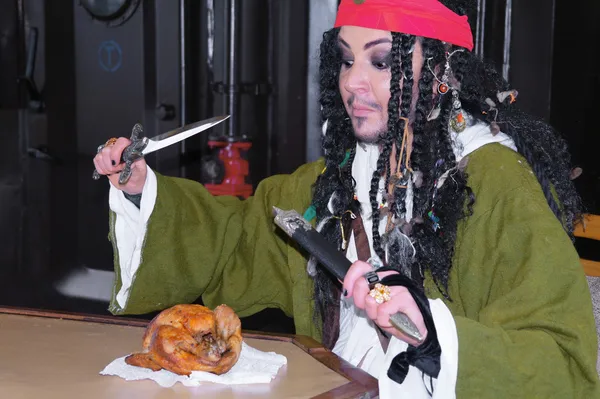 Actor Jack Sparrow in the form of eating chicken grilled on a sailing ship — Stock Photo, Image