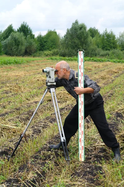 一名老翁与经纬仪测量距离领域 — 图库照片