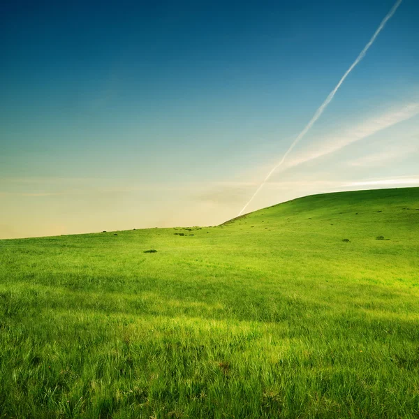 Trace of airplane over green hills — Stock Photo, Image