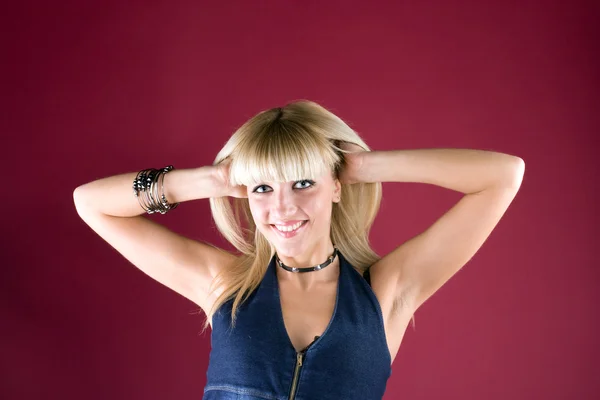 Porträtt av en leende blondin på röd bakgrund — Stockfoto