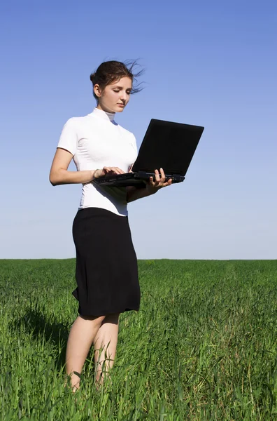 Mladá žena, pracující na notebooku v poli — Stock fotografie