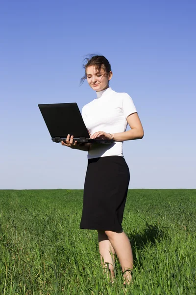 Bella giovane donna d'affari in piedi con il suo computer portatile in un — Foto Stock