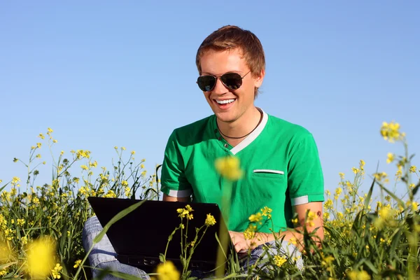 Schattig man op het veld met een laptop — Stockfoto