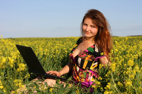 Όμορφη μελαχρινή σε ένα κίτρινο Λιβάδι με laptop — Φωτογραφία Αρχείου