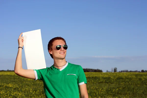 Молодой человек в солнечных очках держит пустую форму — стоковое фото