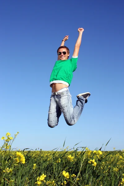 Joven saltando en un campo amarillo en el verano — Foto de Stock