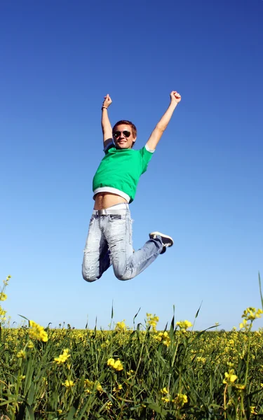 Stilig kille med glasögon hoppar på fältet — Stockfoto