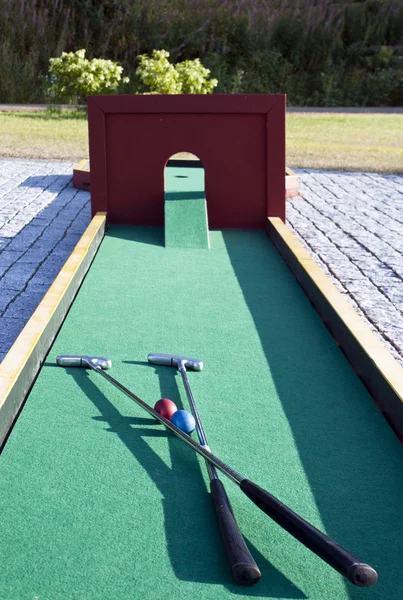Mini golf kulüpleri ve renkli topları üzerinde yeşil örtü seti — Stok fotoğraf