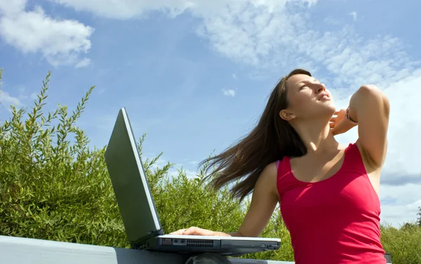 Attraktiv tjej med en bärbar dator i parken — Stockfoto