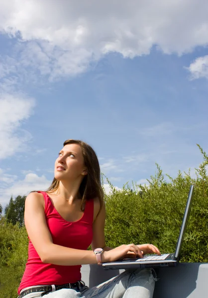 Beautiful brunette p with a laptop in the park — Stock Photo, Image
