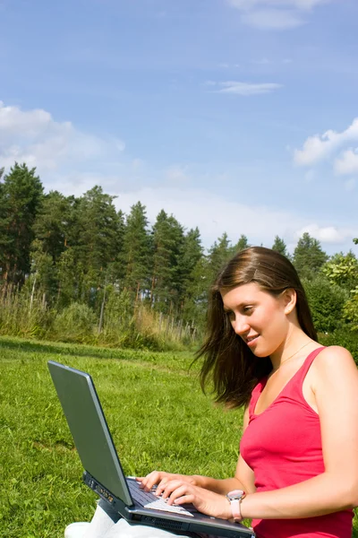 Mooie brunette wordt afgedrukt op een laptop — Stockfoto