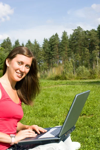 Mooie brunette wordt afgedrukt op een laptop — Stockfoto