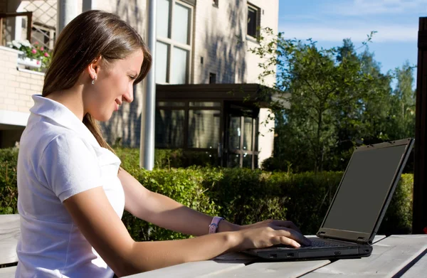 Giovane bella donna con computer portatile seduto sulla panchina in un parco — Foto Stock